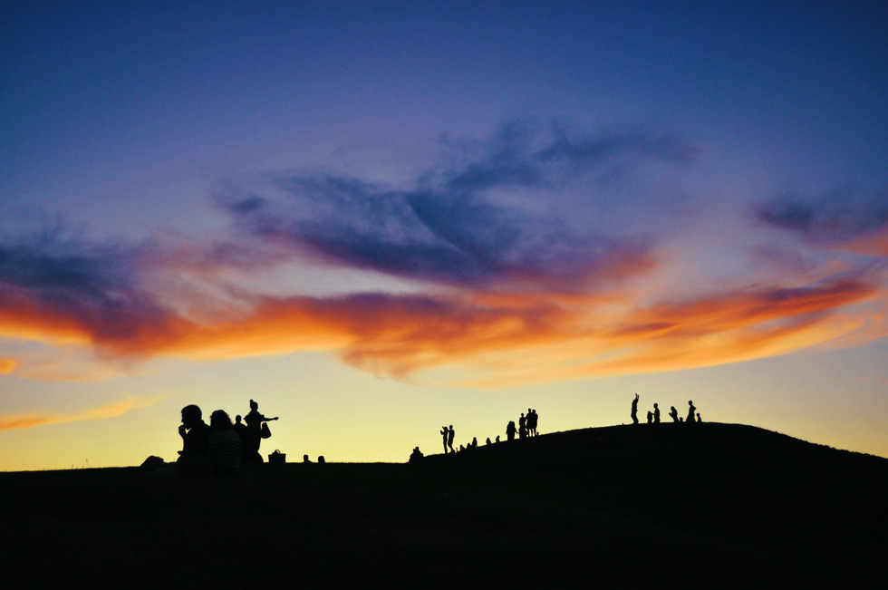 A group of people hiking and enjoying a sunset