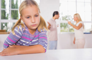 A child stressed about parents arguing in the background