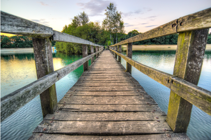 An empty bridge leading over a lake