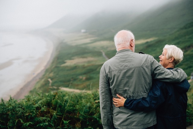 An elderly couple hugging while hiking